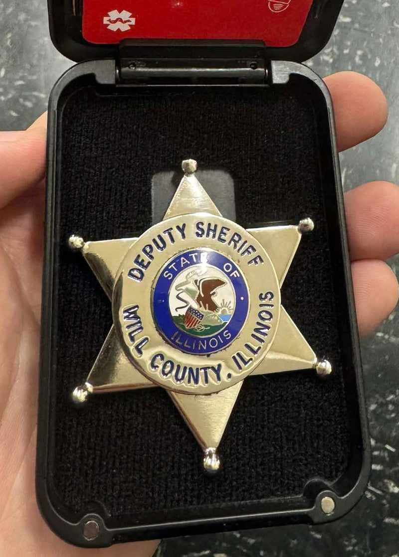Gold star-shaped deputy sheriff badge from the State of Illinois in a badge wallet.